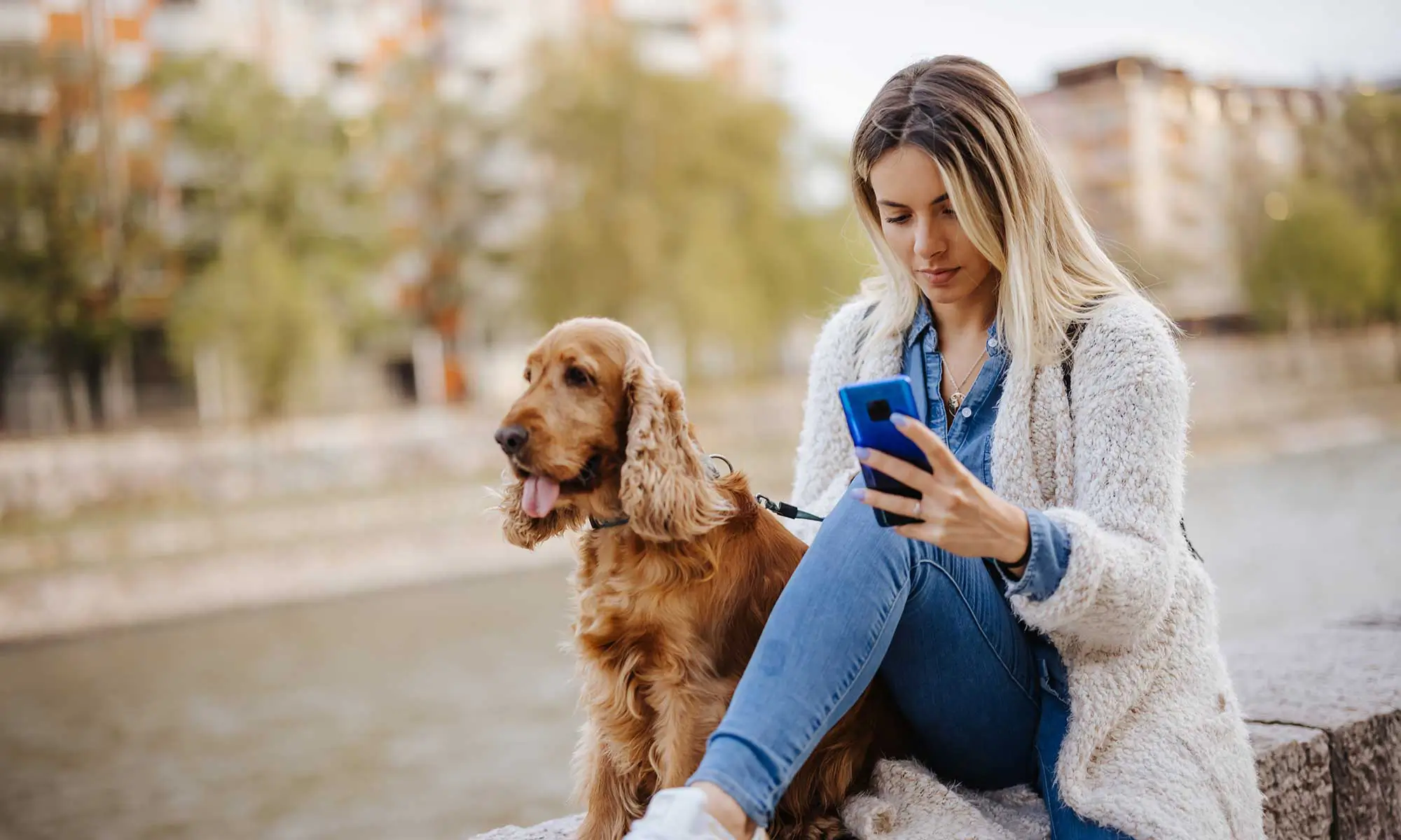 A woman and her dog using the phone